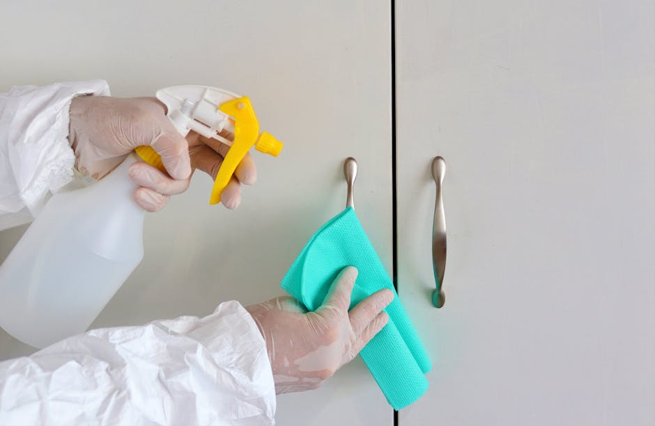 A light blue dustpan and a wooden-handled scrub brush with beige bristles are hanging on a white wall. The dustpan is made of plastic and positioned beneath the brush, which is tilted slightly, showin